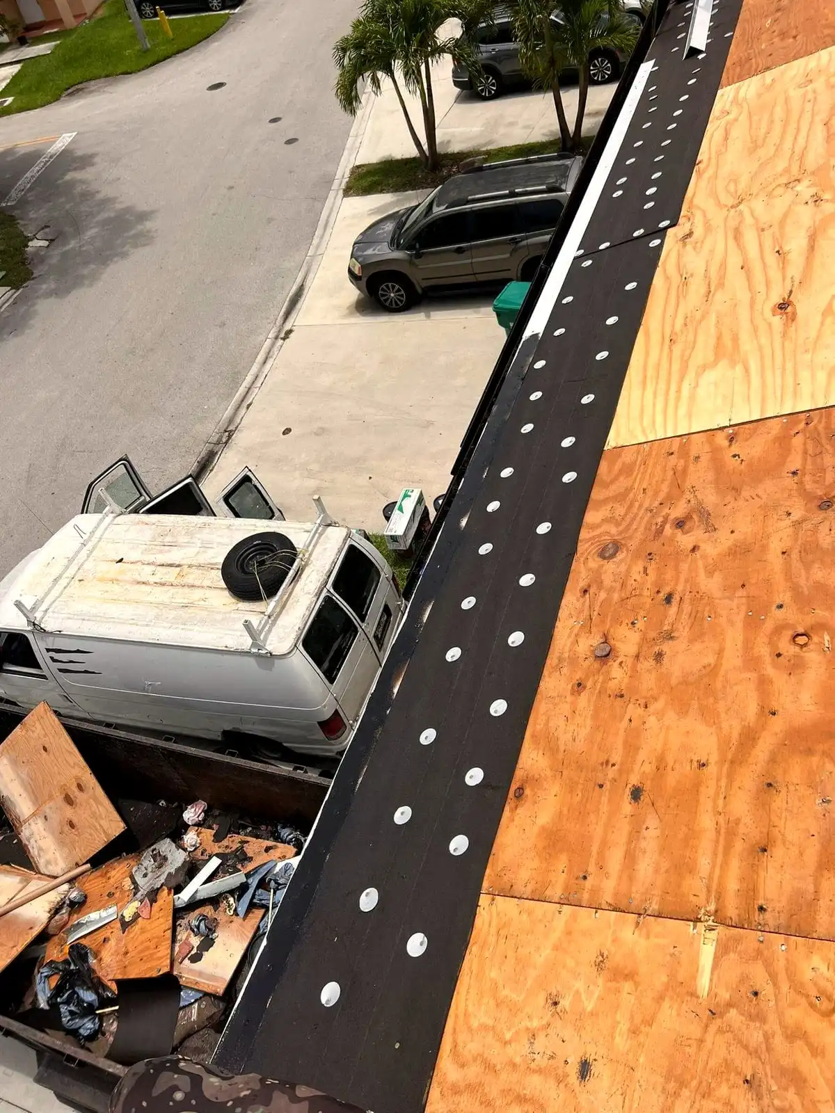 Roof edge dried in after storm damage, with debris loaded in a truck below