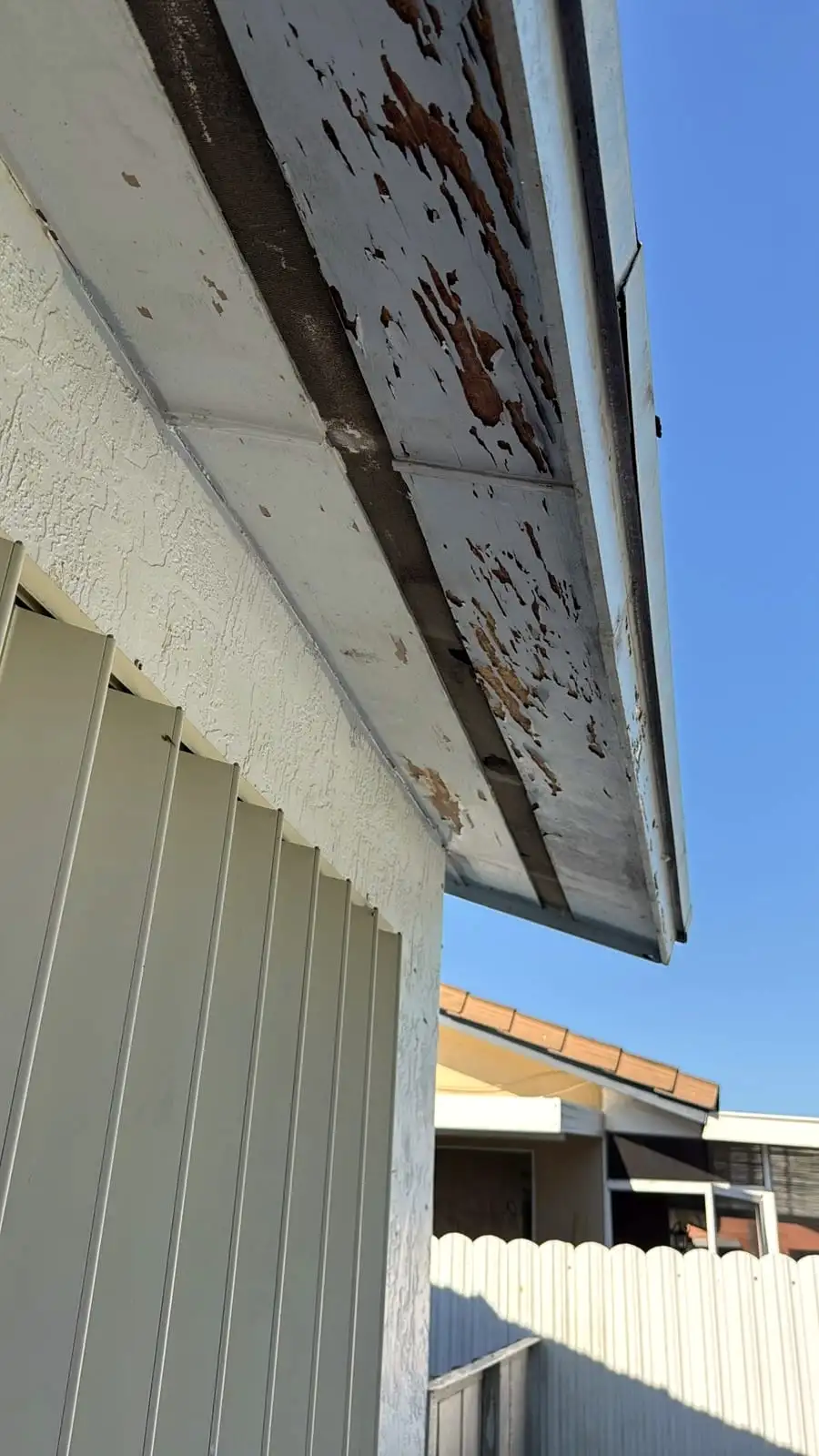 Weathered fascia board along a roof edge where a gutter is mounted