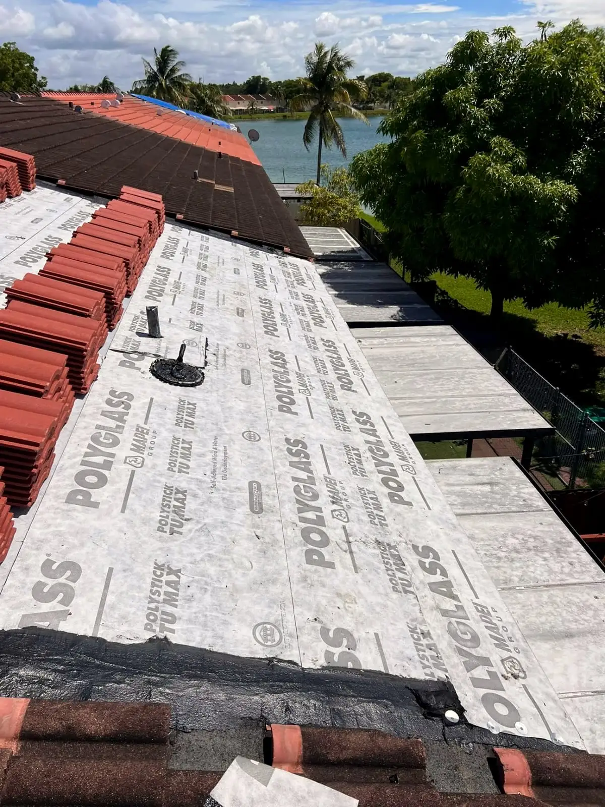 Polyglass underlayment laid on a roof deck with stacks of clay tile ready to install