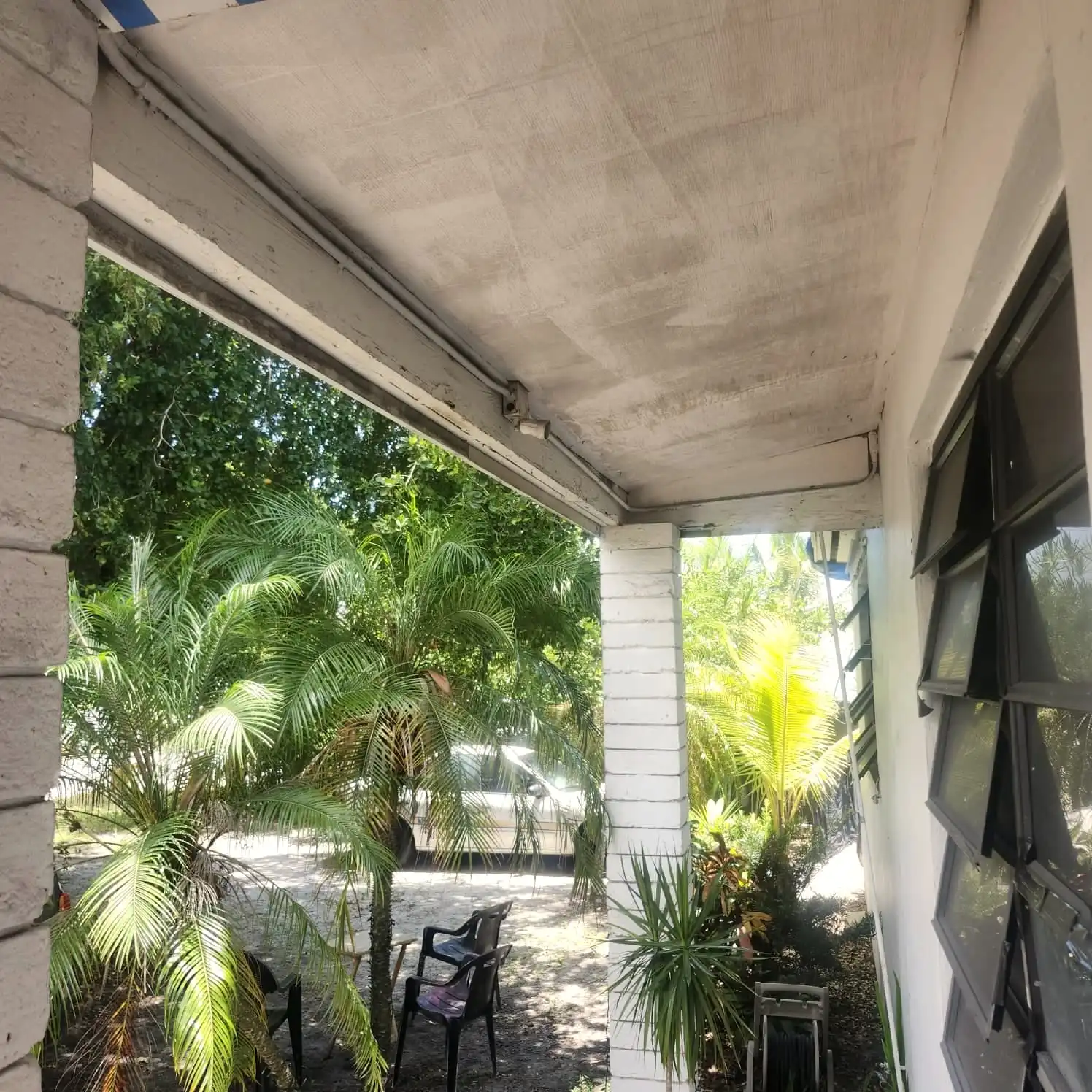 Roof eave and soffit over a covered porch with palm trees beyond